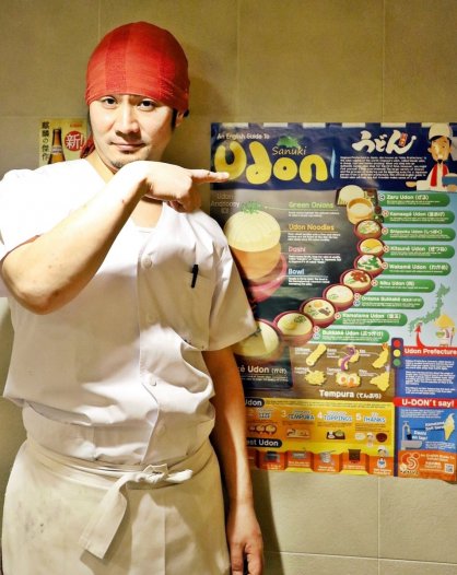 外国人客がうどんを安心して食べられるよう製作したポスターと店主の米津さん＝香川県高松市田町