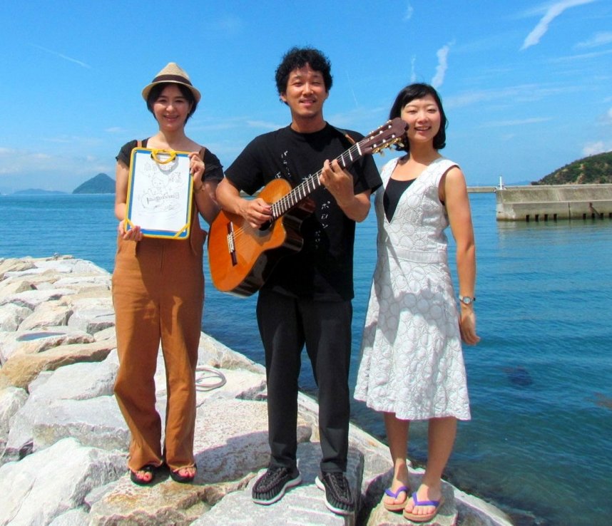 「あるある直島」を制作した福島節さん（中央）。右は妻の真希さん、左は漫画家のまつざきしおりさん＝直島町
