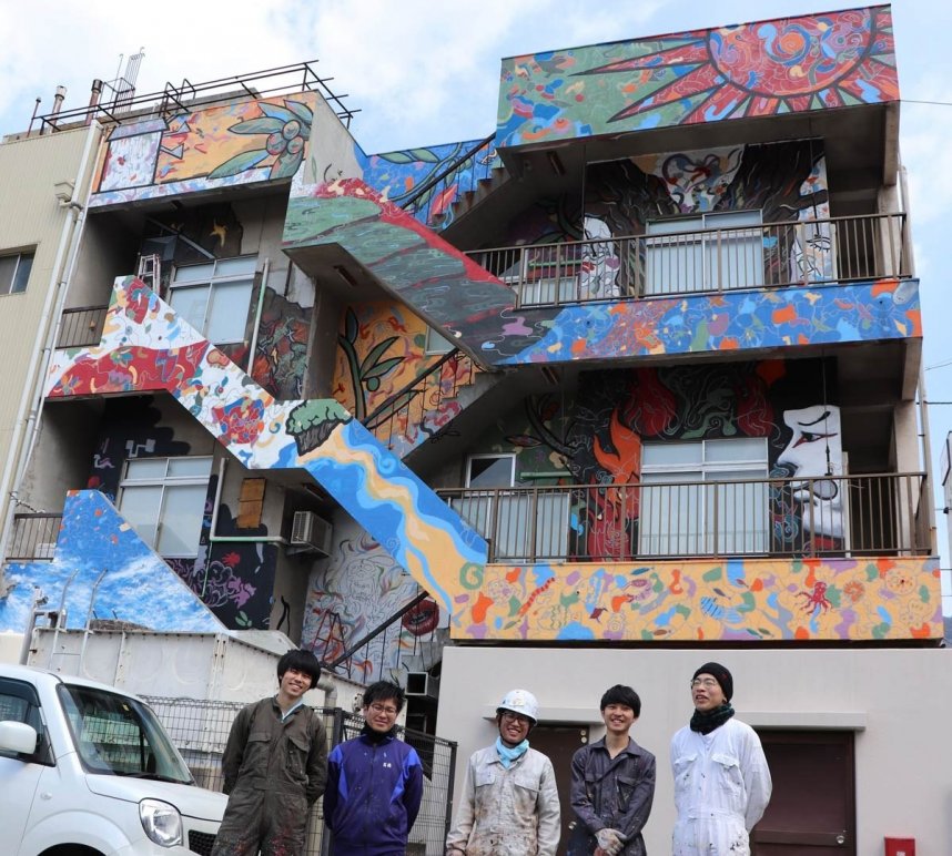 建物壁面への絵画を完成させ、満足感を漂わせる神薗さん（中央）ら多摩美術大の学生たち＝土庄町