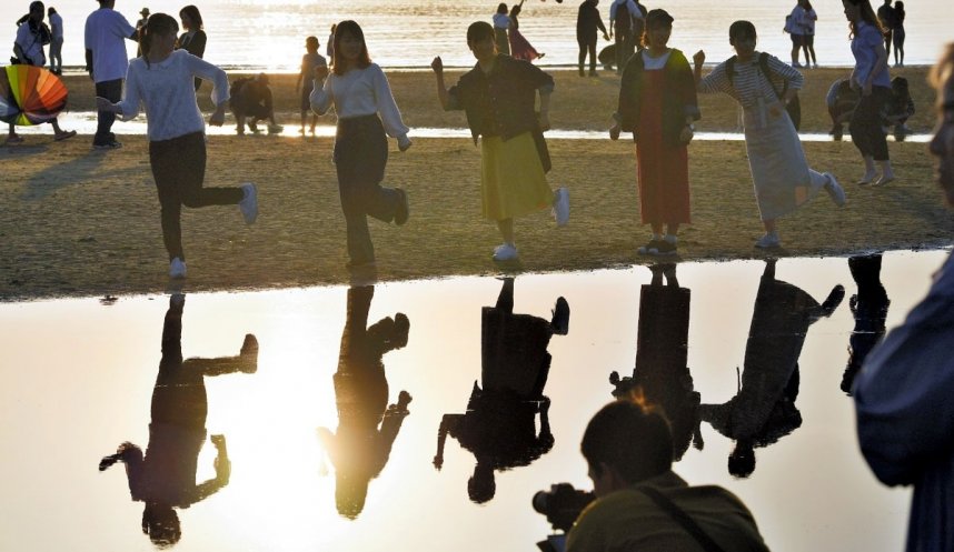 鏡のようになった潮だまりの近くでポーズを取る観光客ら＝三豊市仁尾町