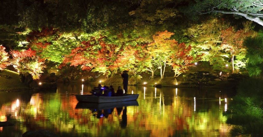 試験点灯で湖面に鮮やかに映し出された紅葉＝香川県高松市栗林町