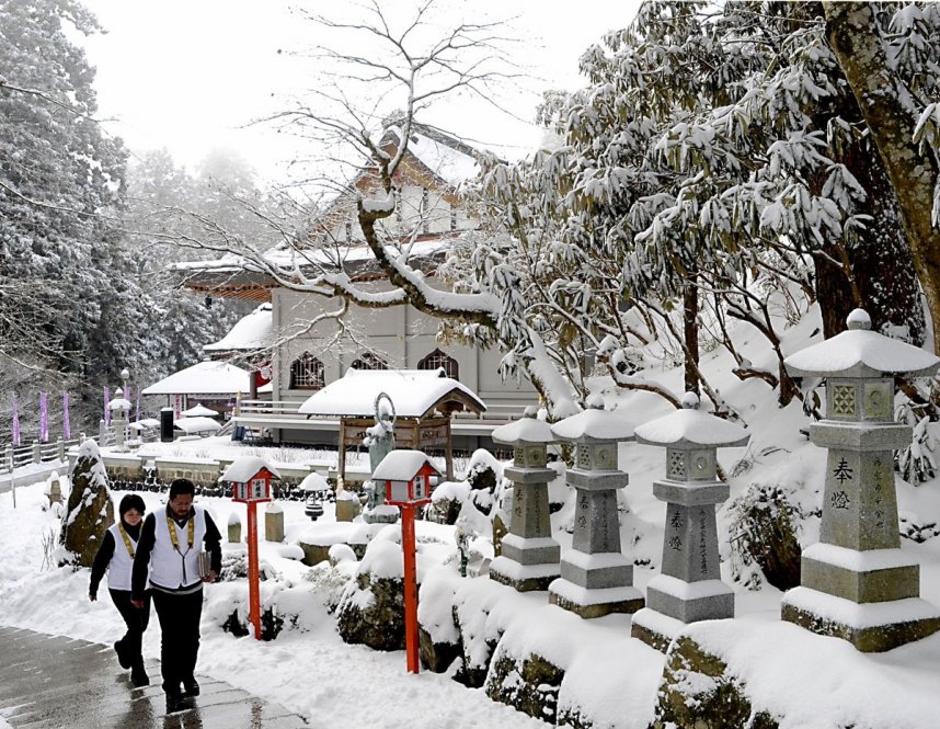 雪景色の雲辺寺境内を歩くお遍路さん（資料）