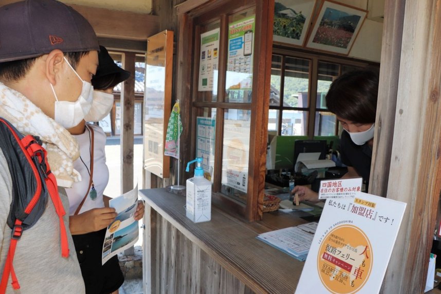 キャンペーンのＰＲチラシにスタンプを押してもらう観光客＝香川県小豆島町田浦、二十四の瞳映画村