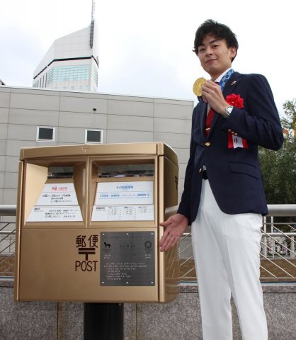 ＪＲ高松駅前に設置されたゴールドポストと記念写真に納まる宇山選手＝香川県高松市浜ノ町