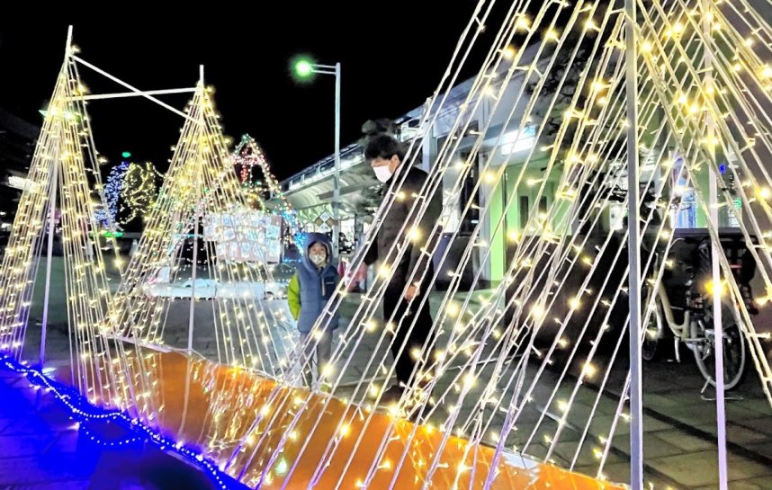 美しい光を放つイルミネーションを楽しむ家族連れ＝香川県坂出市元町、ＪＲ坂出駅前