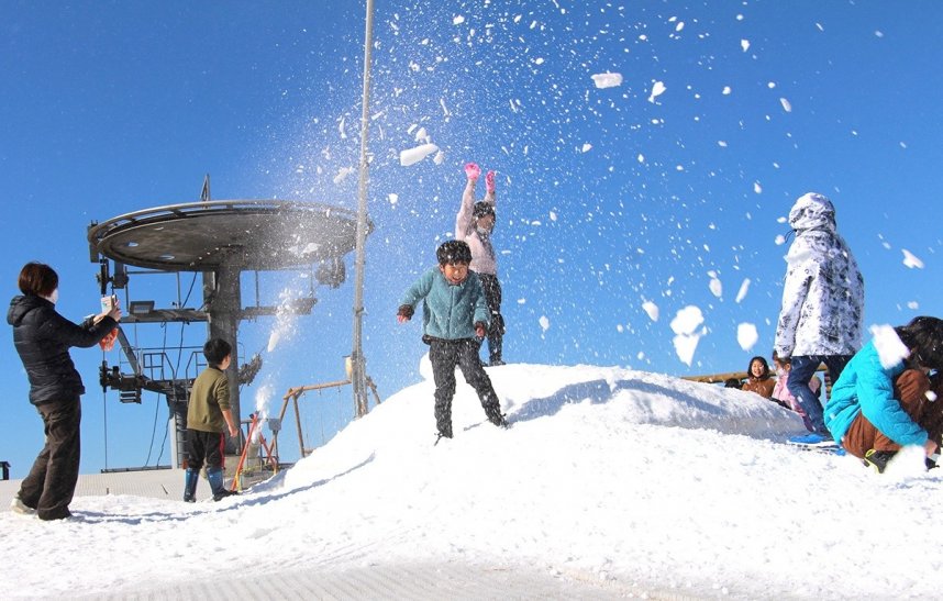 噴き出される人工雪の感触を楽しむ子どもたち＝香川県観音寺市大野原町、雲辺寺山頂公園