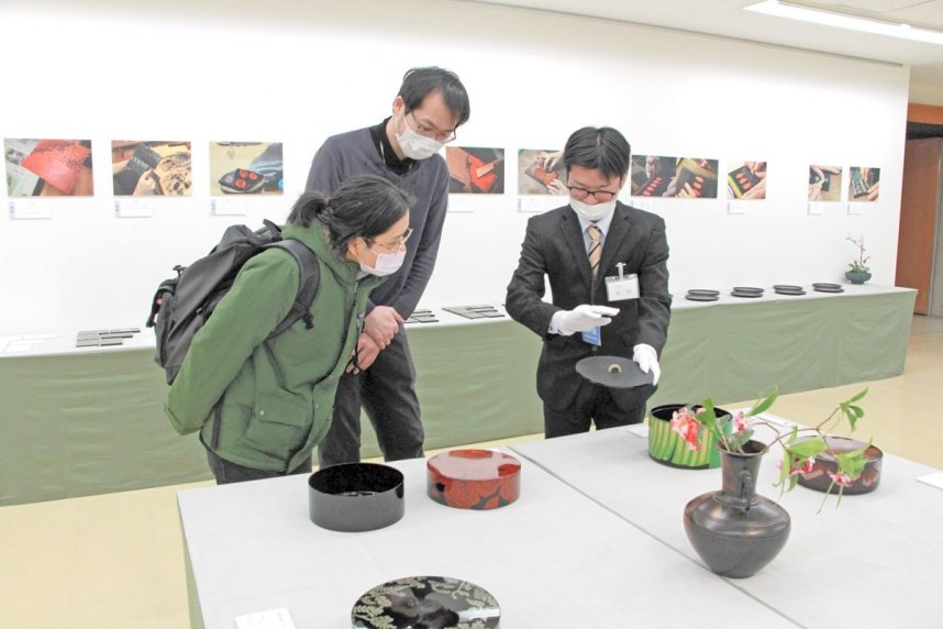 担当者（右端）から出品作についての説明を聞く来場者＝香川県高松市番町、香川県文化会館