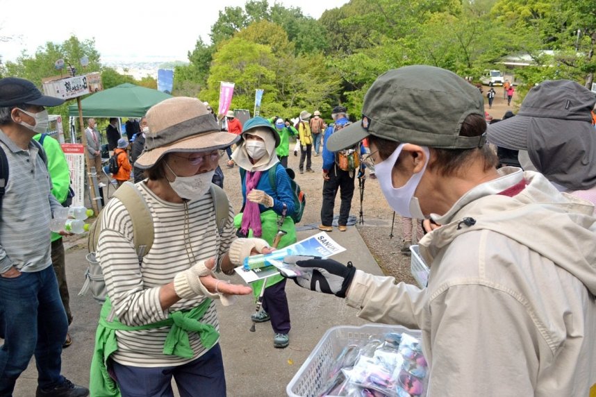 飯野山の山開き式の後、記念の缶バッジを受け取る参加者