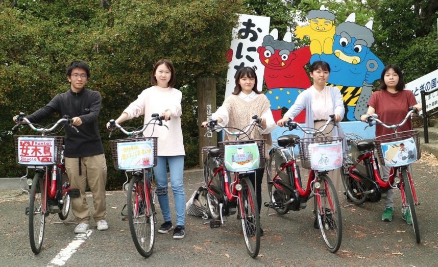 イラストを取り付けたレンタル自転車と穴吹デザインカレッジの学生＝香川県高松市、女木島