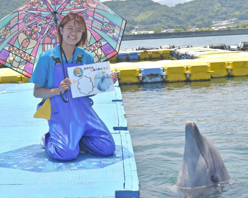 雨の日のキャンペーンなどをＰＲする施設スタッフとイルカ＝香川県さぬき市津田町