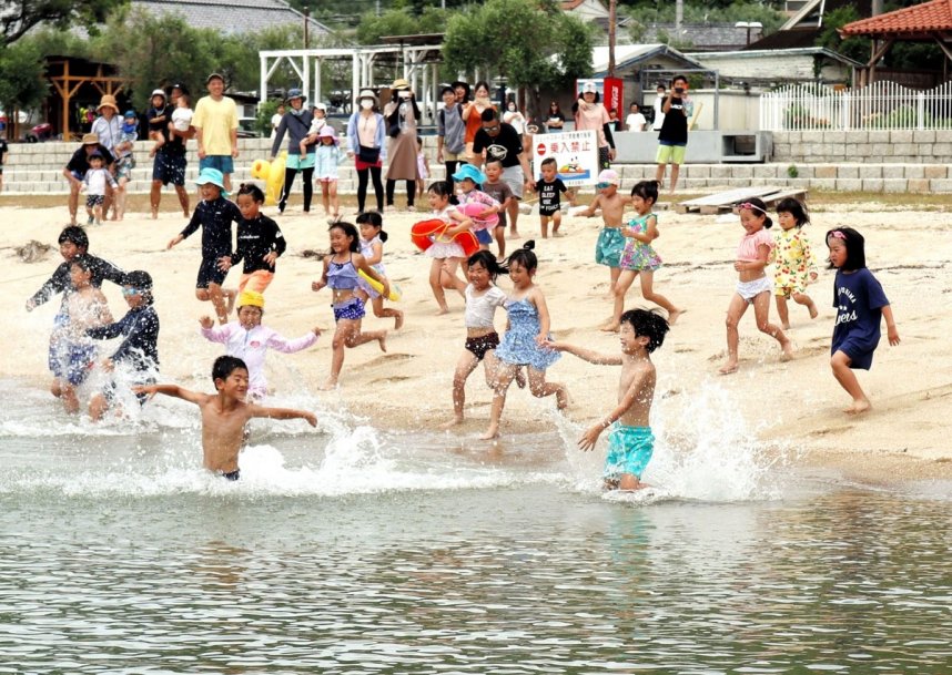 海開きを迎え、歓声を上げながら一斉に海に入る子どもたち＝７月３日、小豆島町西村のオリーブビーチ