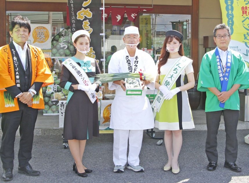 ＰＲ大使から青ネギとスダチを受け取った香川社長（中央）＝香川県高松市松縄町