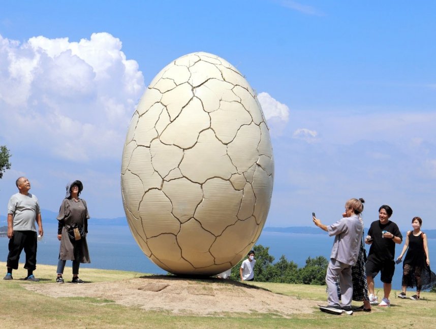 巨大な卵形の新作「はじまりの刻」に見入る来場者＝土庄町屋形崎