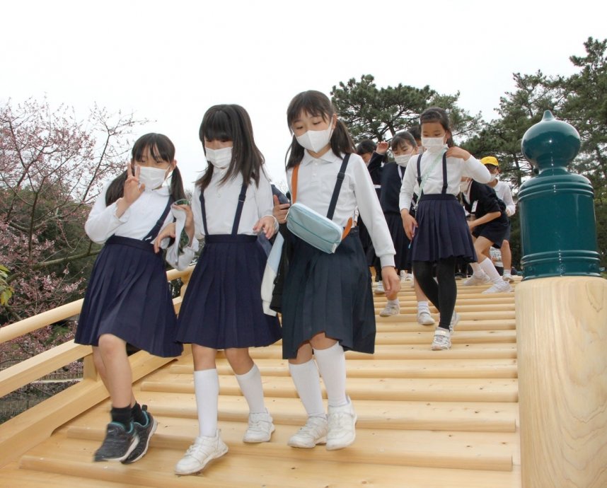 新たに架け替えた偃月橋の渡り初めを行う児童ら＝香川県高松市栗林町、栗林公園