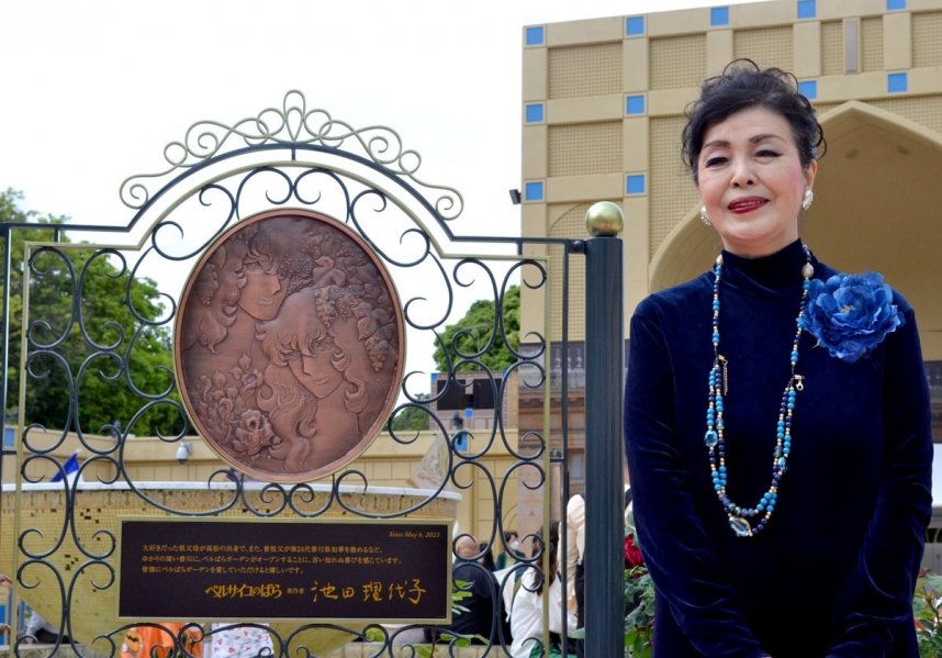 銅板モニュメントの横で笑みを浮かべる池田さん