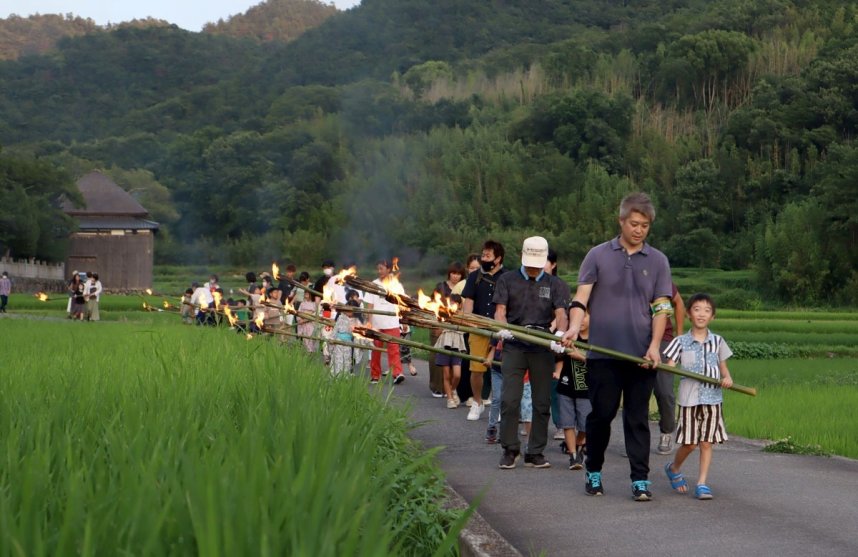 水田に火手の炎をかざしながら、ゆっくりと歩く親子連れら＝香川県土庄町肥土山