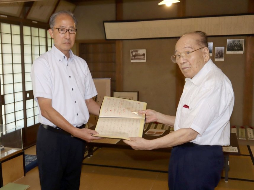 港教育長（左）に尾崎放哉が添削した跡のある俳句原稿を手渡す岡田会長＝土庄町、小豆島尾崎放哉記念館