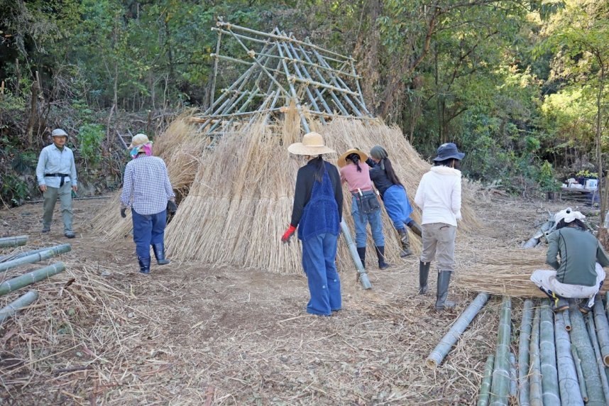 地元の竹やヒノキで組んだ柱にかやをかぶせて縄文小屋を作る地域住民ら