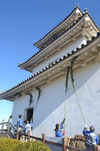 竹のほうきで１年間の汚れを落とす職員ら＝香川県丸亀市一番丁、丸亀城