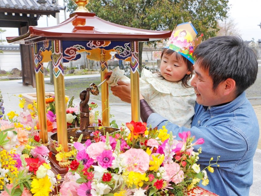 花で飾られた釈迦像に甘茶をかける親子＝香川県善通寺市弘田町、甲山寺