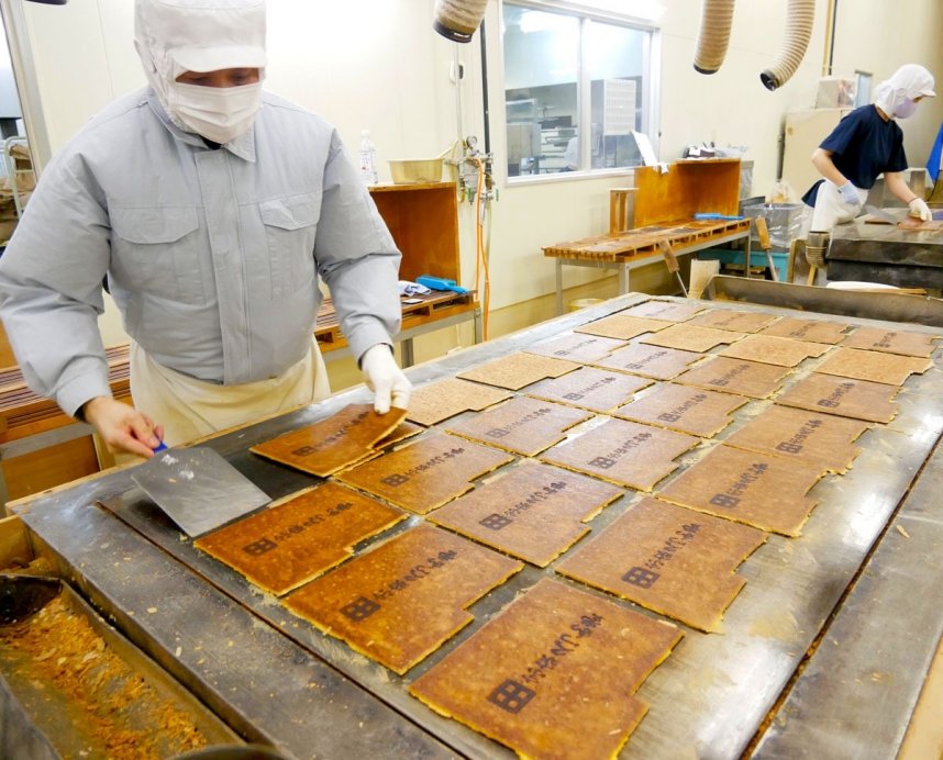 看板商品の瓦せんべいを焼き上げる職人＝香川県高松市郷東町、西店工場