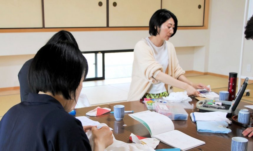 赤ちゃんの肌着に丁寧に糸を縫い付ける参加者＝香川県善通寺市金蔵寺町、金倉寺