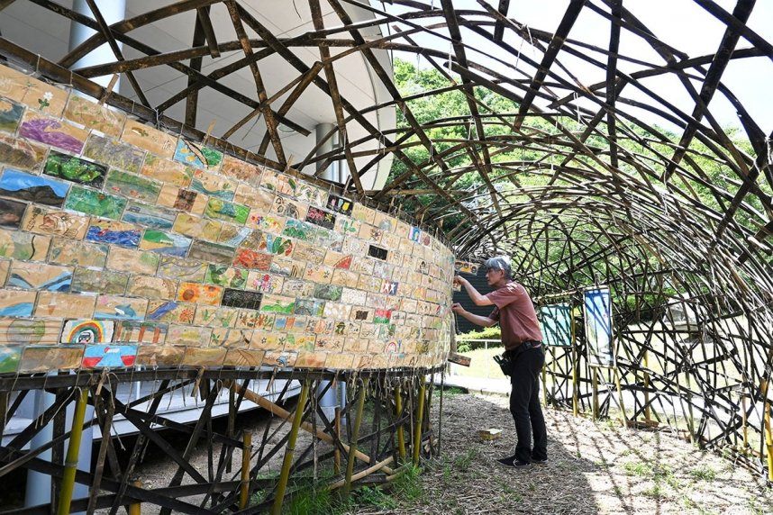 竹で作ったトンネルに児童らの作品を掲示していく塩江美術館の職員＝高松市塩江町