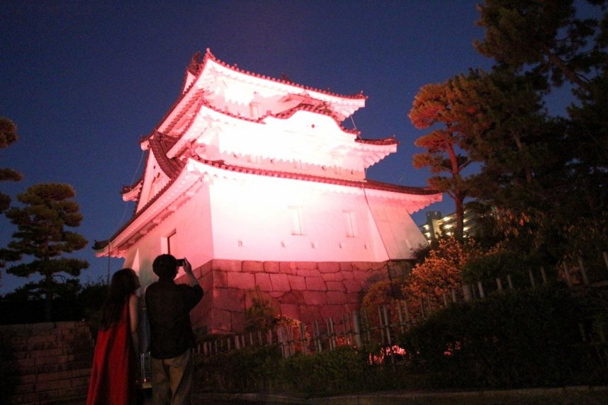 赤色にライトアップされた艮櫓の幻想的な光景に見入る来園者＝香川県高松市玉藻町、玉藻公園