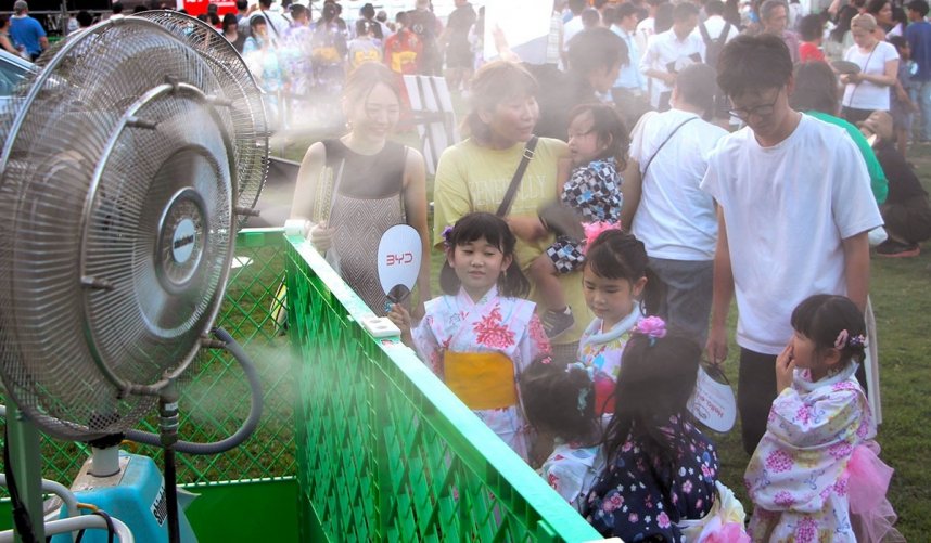 ミスト扇風機で涼を取る来場者＝高松市中央公園