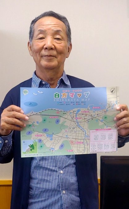 白方地区の地図を手にまち歩きをＰＲする中津会長＝多度津町役場