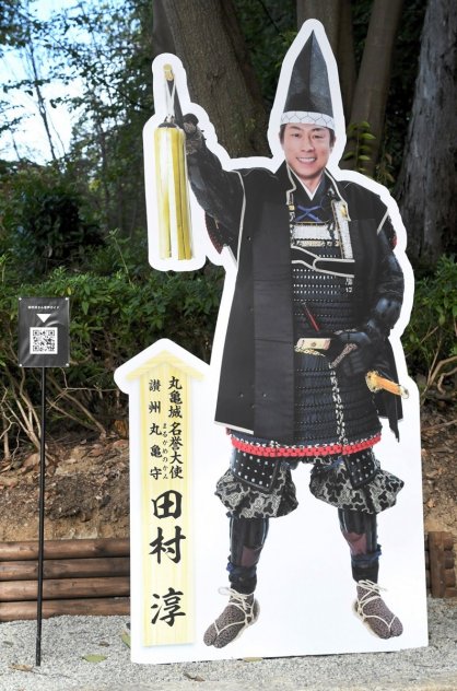 見返り坂にお目見えした田村淳さんの等身大パネル。傍らには音声案内用のＱＲコード付きスタンドが設置されている＝香川県丸亀市一番丁、丸亀城