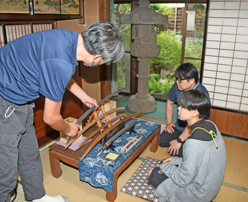 ニッカリ青江脇指などの模造刀を前に刀の解説を受ける来館者（右端）。奥は石灯籠＝香川県仲多度郡多度津町家中、町立資料館