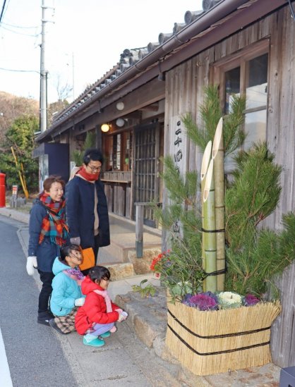 地元の材料で手作りされた門松に見入る家族連れ＝香川県小豆郡小豆島町田浦、二十四の瞳映画村