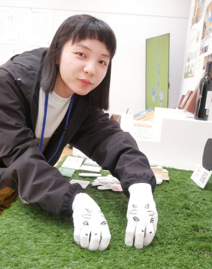 ヤギの軍手をはめて草抜きの動きをする加藤さん＝高松市紺屋町、市美術館