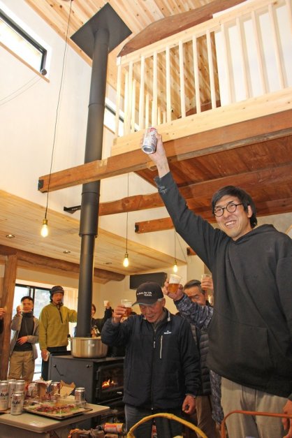 内覧会で地域住民と共に施設の完成を喜ぶ飯村さん（右端）。１階には薪ストーブも備えている