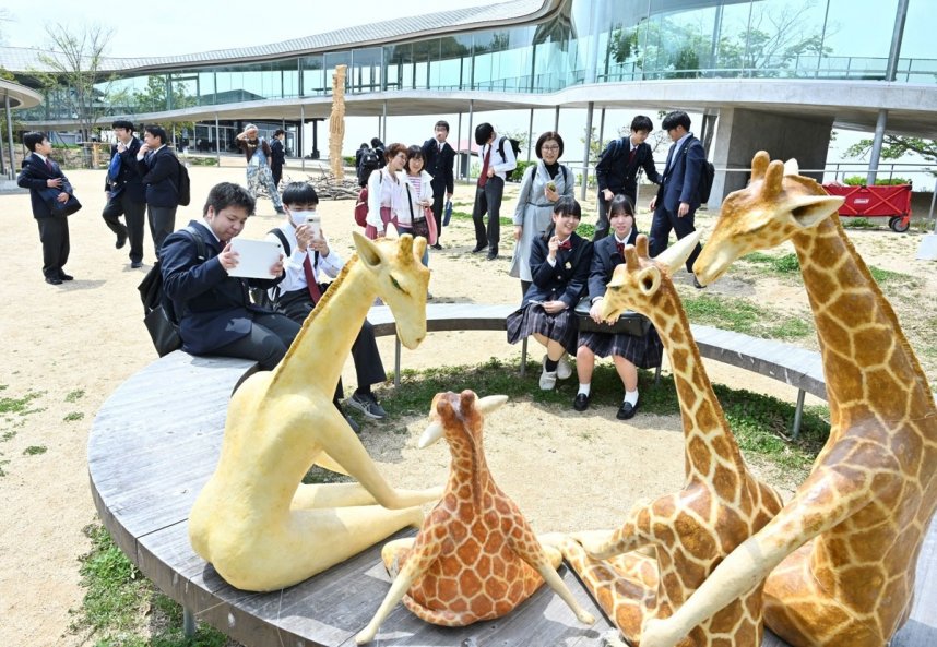 キリンなど動物をかたどった作品を写真に収める来場者たち＝香川県高松市屋島東町、屋島山上交流拠点施設「やしまーる」