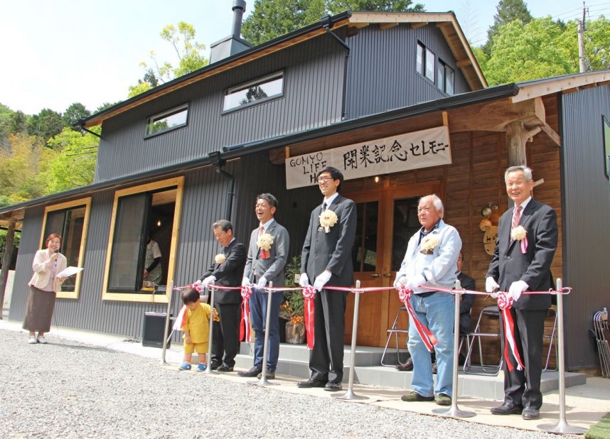 オープンを記念してテープカットを行う飯村代表（右から３人目）や上村市長（同４人目）ら