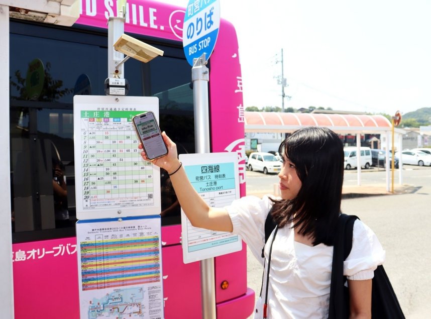 「ｔｅｂｕ―Ｒｉｄｅ　ＰＡＳＳ」を利用して路線バスに乗車する実証実験の参加者。時刻表の上部に設置されているのがビーコン＝香川県小豆郡土庄町、土庄港バス停