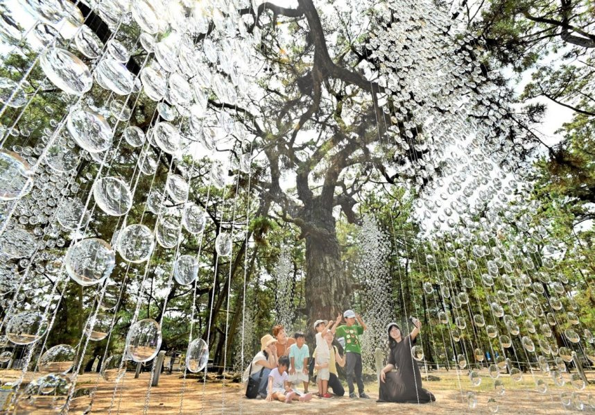 津田の松原に初めて設置されたアート作品。個性的な造形美を背景に写真を撮る来場者＝さぬき市津田町