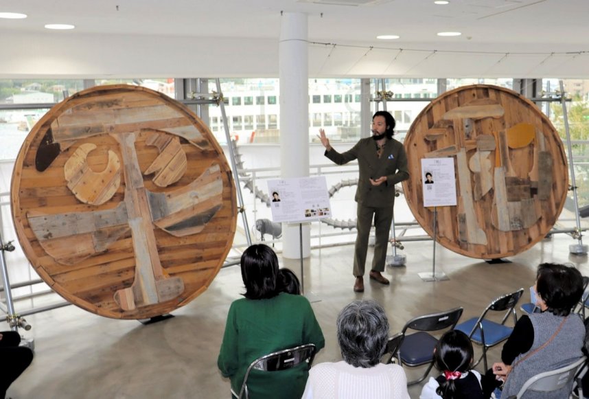 大阪・関西万博会場から移設した自身のアート作品について来場者に説明する青木さん＝香川県小豆郡土庄町、土庄港ターミナル