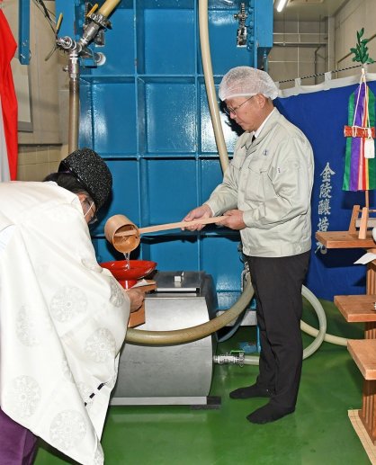 神前に供える新酒を注ぐ酒井製造課長（右）＝香川県仲多度郡多度津町葛原、西野金陵多度津工場