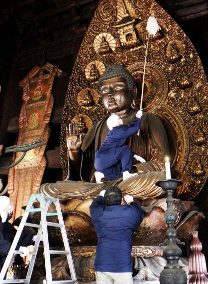 本尊のほこりをはたきで払い落とす僧侶ら＝香川県善通寺市、総本山善通寺