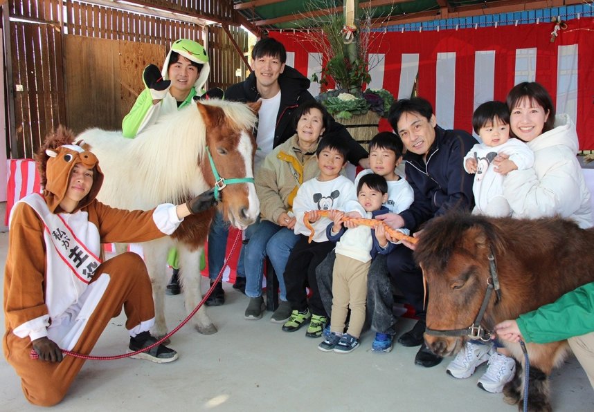 馬に主役をバトンタッチした干支の引き継ぎ式で記念写真に納まる家族連れら＝香川県東かがわ市松原、しろとり動物園