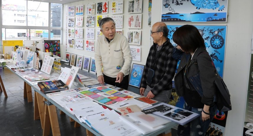 これまでの作品を前に、来場者と談笑する藤本さん（左端）＝香川県高松市北浜町