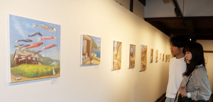 映画村で暮らすネコの日常と四季の移ろいを捉えた絵画に見入る来館者＝香川県小豆郡小豆島町田浦、二十四の瞳映画村