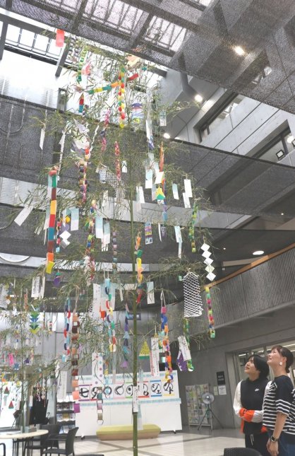 吹き抜けのロビーに展示されたササ飾りに見入る来場者＝香川県善通寺市文京町、ＺＥＮキューブ