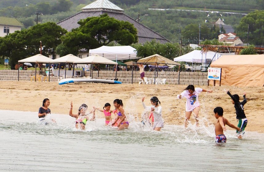 歓声を上げながら砂浜を駆け抜けて海に飛び込む子どもたち＝香川県小豆郡小豆島町西村、オリーブビーチ