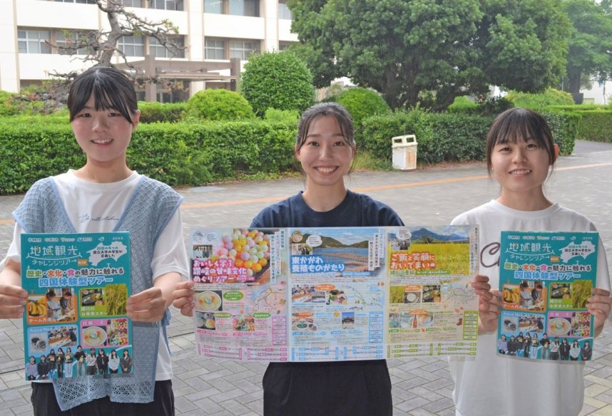 旅行商品が掲載されたパンフレットを掲げてアピールする学生たち＝香川県高松市幸町、香川大